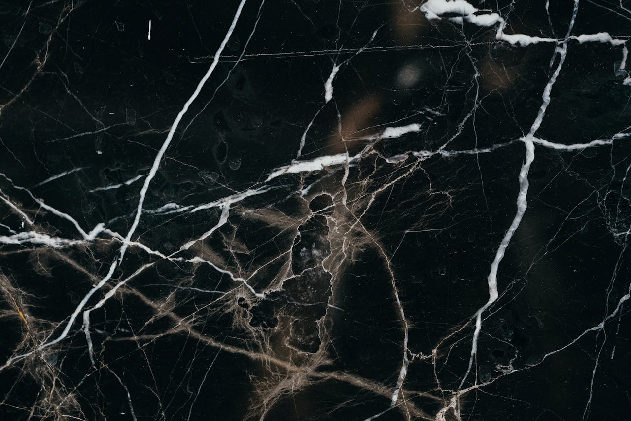 Close-up view of a black marble texture, showcasing intricate white veining patterns.