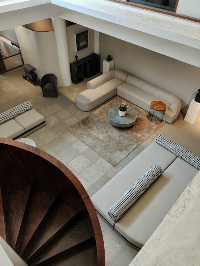 Spacious minimalist living room with sofas and spiral staircase view.